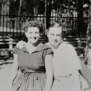 Black-and-white family photograph of a couple seated together outdoors.